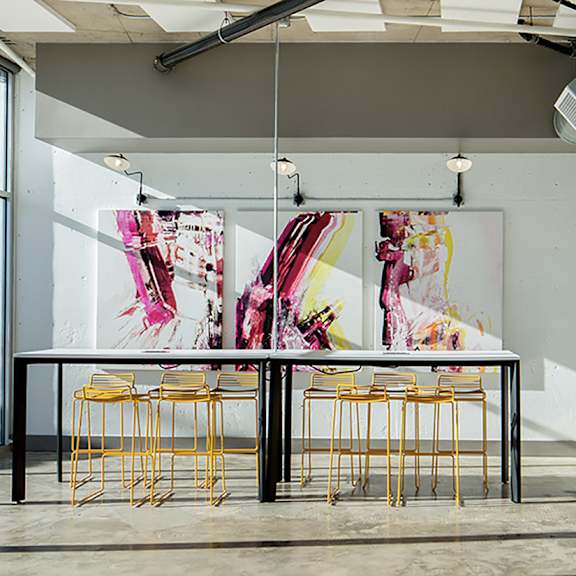 a room with a table and chairs and a painting on the wall.