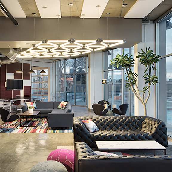 a modern living room with a black sofa and a glass wall.