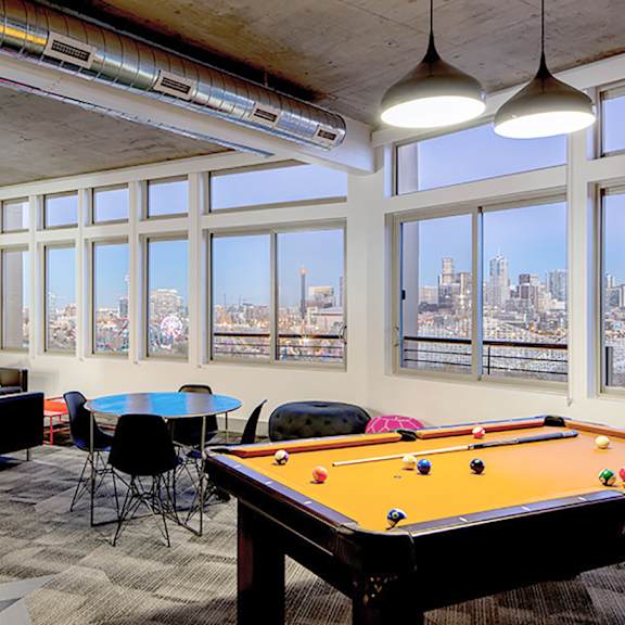 a room with a pool table and a view of the city.
