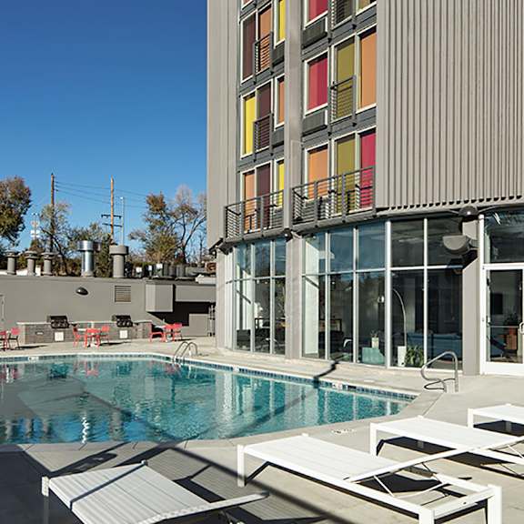 a swimming pool is surrounded by sun loungers in front of a modern building.