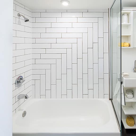 a white bathroom with a white tub and a white sink.