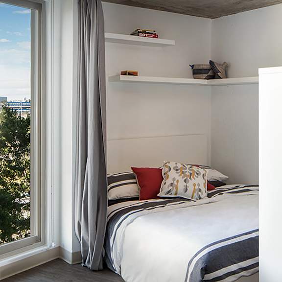 a bedroom with a bed, pillows, and a window with curtains.