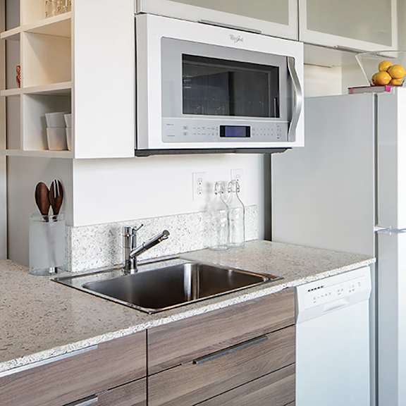 a modern kitchen with a white refrigerator, microwave, and dishwasher.