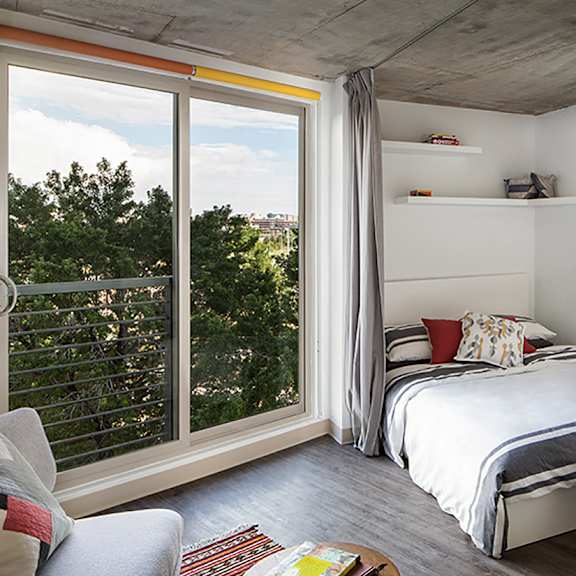 a bedroom with a bed, a chair, and a window with a view of trees.