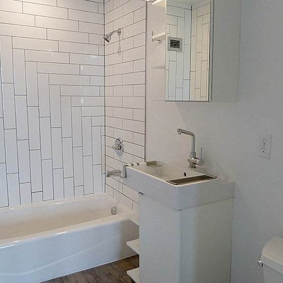 a white bathroom with a tub, sink and mirror.