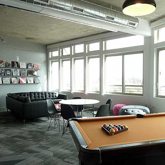a pool table is in the middle of a room with a couch and chairs.