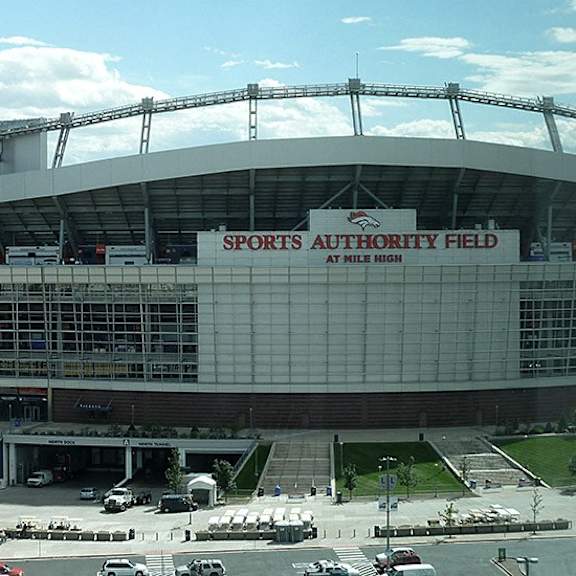 a large stadium with a glass facade and a sign that reads