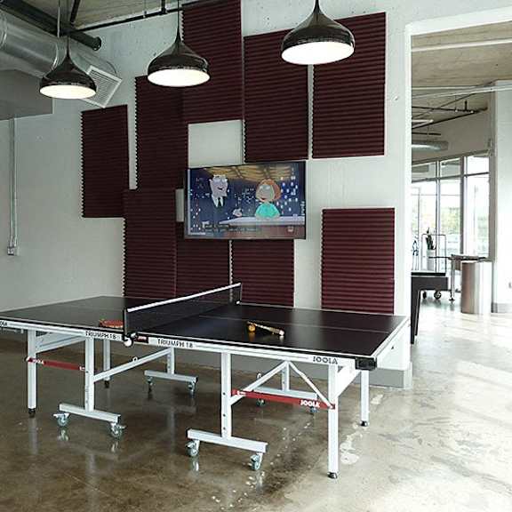 a ping pong table is in the middle of a room with a tv on the wall.