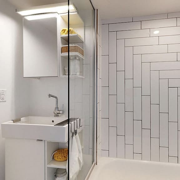 a white sink with a white cabinet and a white bathtub in a bathroom.