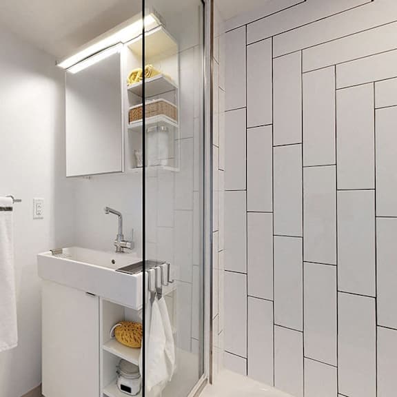 a white bathroom with a sink, mirror, and towel rack.