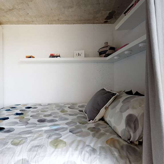 a bed with a grey and white patterned comforter and a grey pillow is in the foreground of the image.