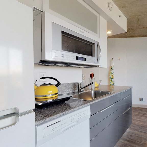 a modern kitchen with a white refrigerator, a yellow kettle, and a grey countertop.
