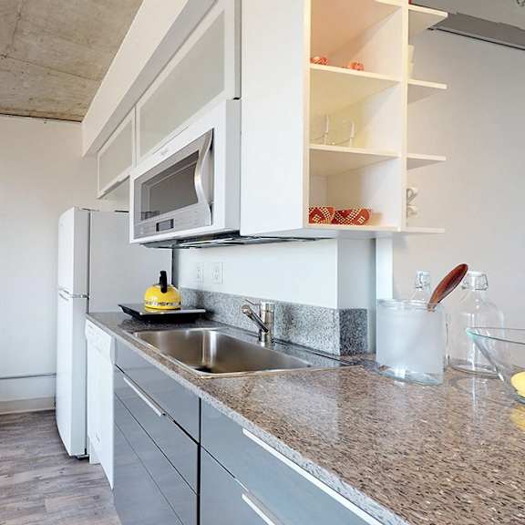 a modern kitchen with a white countertop and a television on the side.