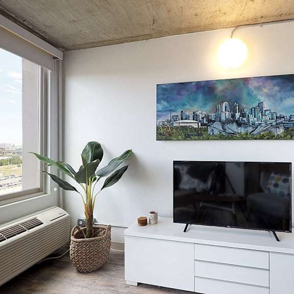 a room with a television, a plant, and a painting on the wall.