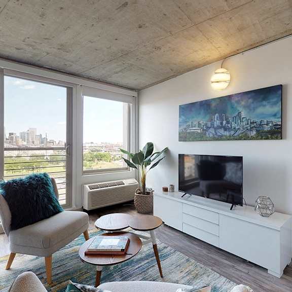 a living room with a chair, a table, a potted plant, and a painting on the wall.