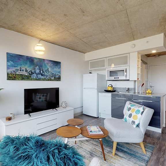 a living room with a blue rug and a painting on the wall.