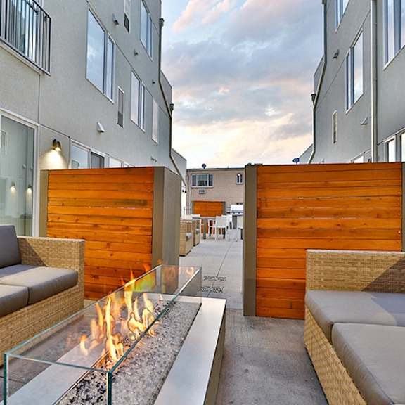 a modern patio with a fire pit and seating area.