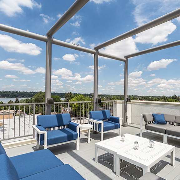 a white table with a glass top sits on a patio with blue cushions.