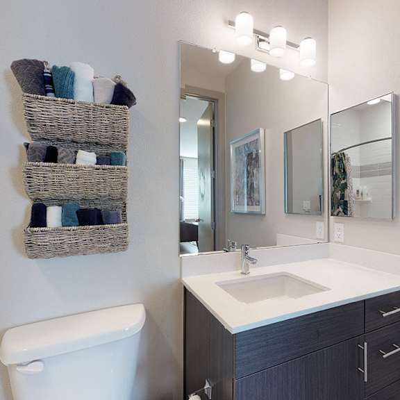 a bathroom with a white toilet, a sink with a cabinet and a mirror.