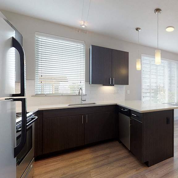 a modern kitchen with dark brown cabinets and a white refrigerator.