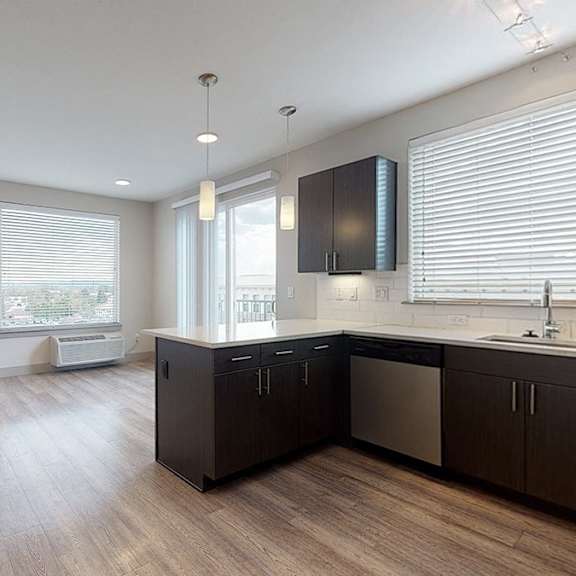 a kitchen with dark wood floors and white walls.