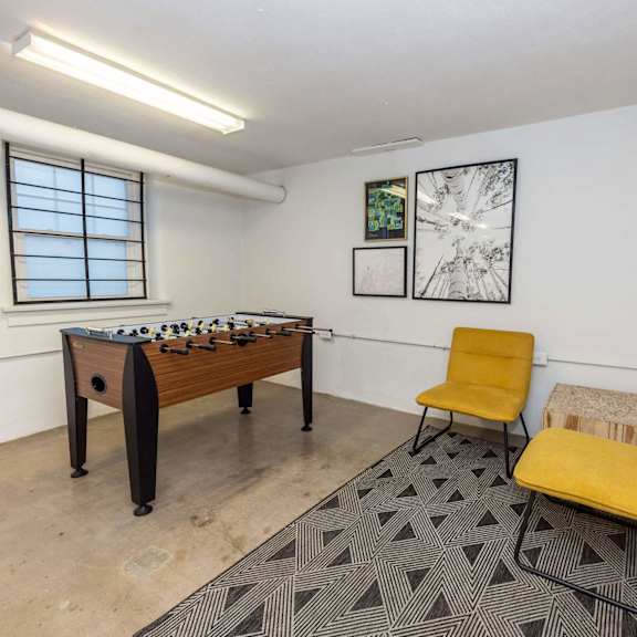 a room with a foosball table, two chairs, and a bench.