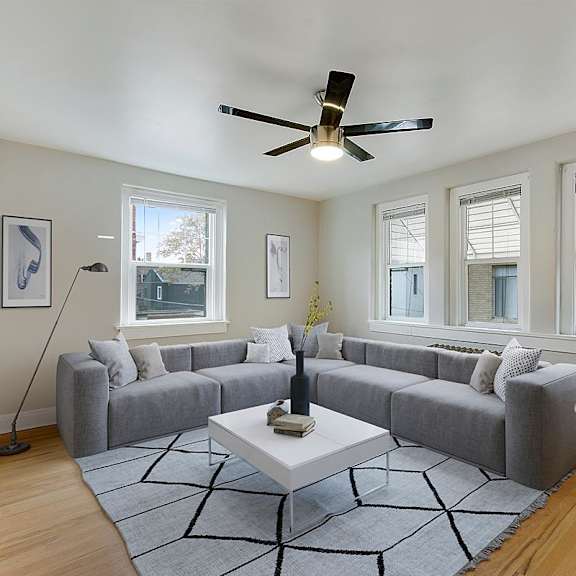 a living room with a grey couch, a white coffee table, and a ceiling fan.