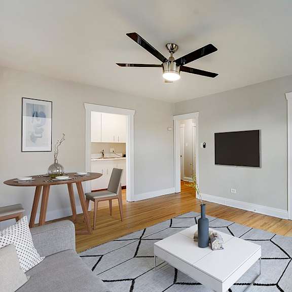 a living room with a grey sofa, a white coffee table, a ceiling fan, and a television.