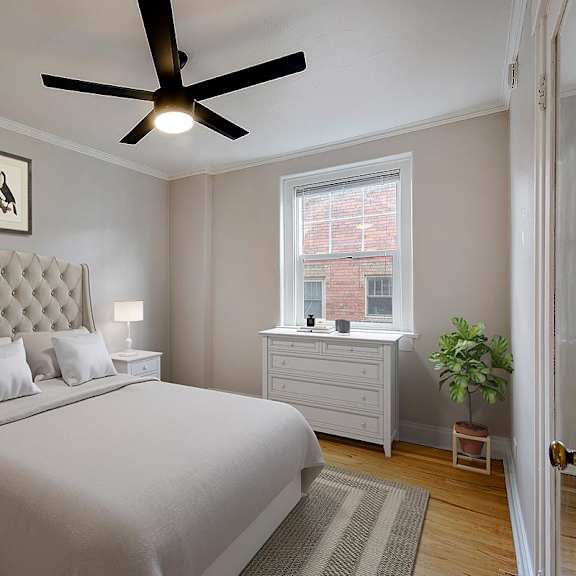 a bedroom with a large bed, a ceiling fan, and two framed pictures on the wall.