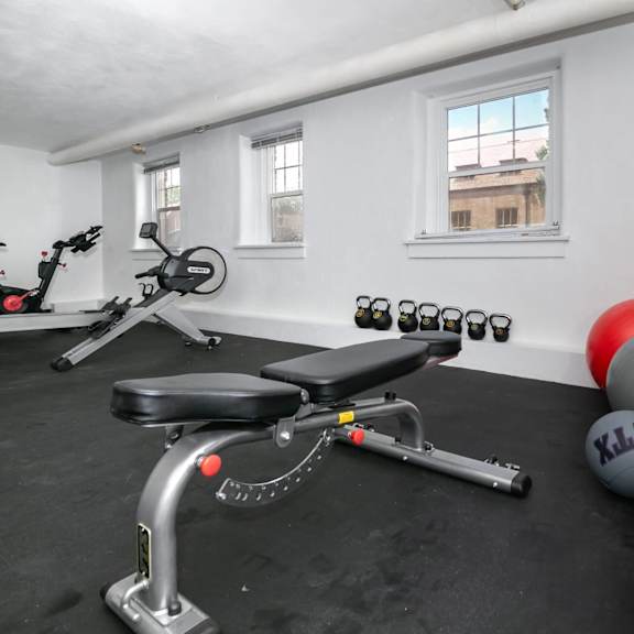 a gym room with a stationary bike, a rowing machine, and a set of dumbbells.