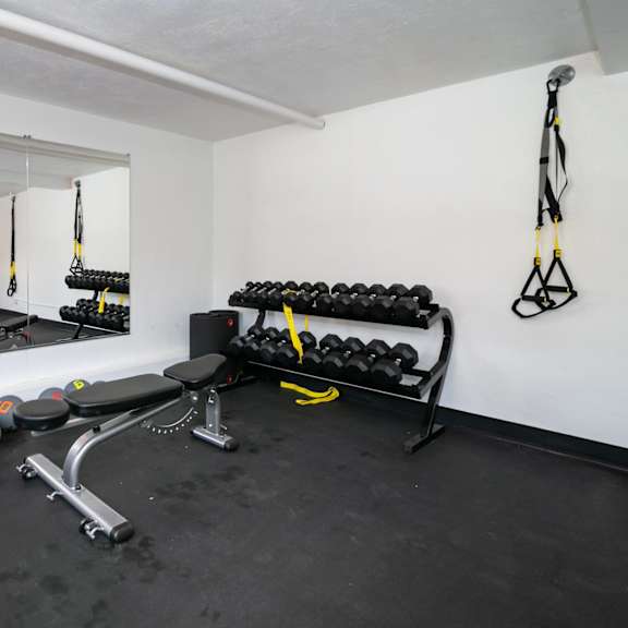 a gym room with a mirror, weights, and exercise equipment.