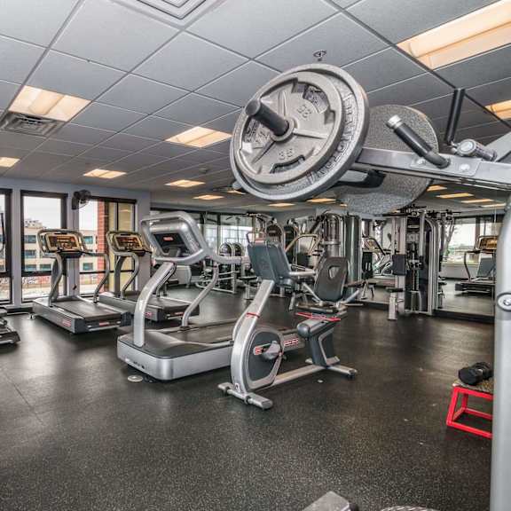 a gym with a variety of equipment including treadmills, weights, and exercise machines.