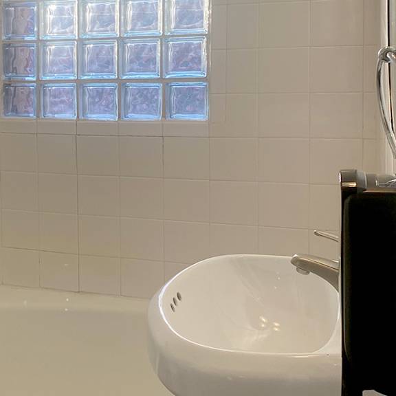 a white bathroom with a tub, sink and window.
