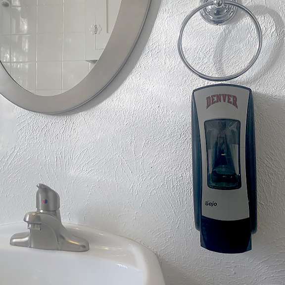 a white sink with a denver water filter on the wall.