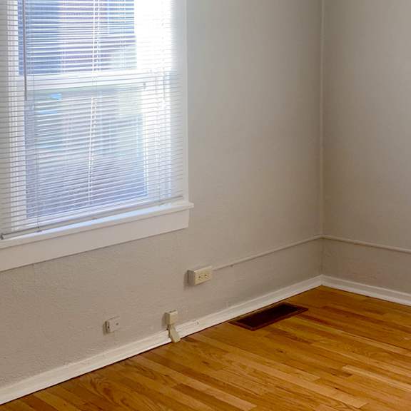 a room with wooden floors and a window with blinds.