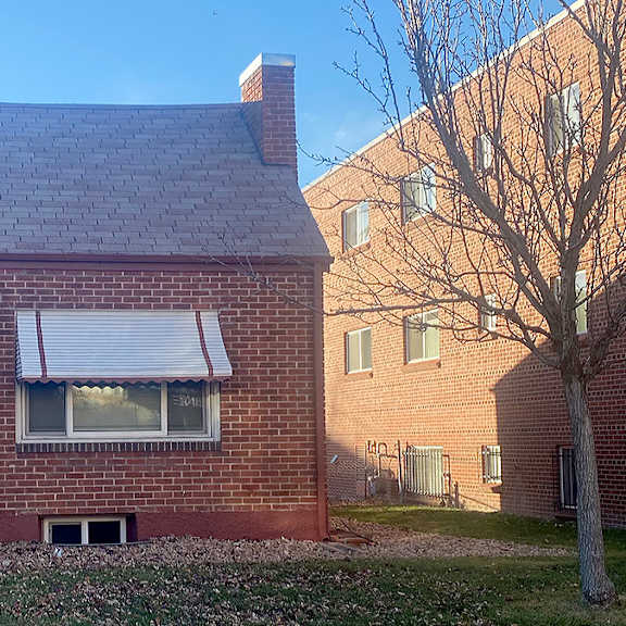 a red brick house with a white door and a small porch.