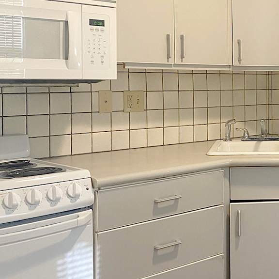 a white kitchen with a microwave, stove, dishwasher, and washing machine.