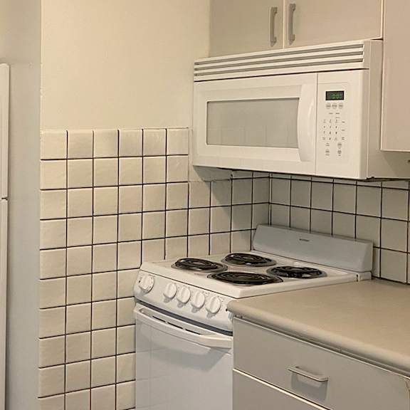 a white refrigerator and a white microwave above a white stove in a kitchen.