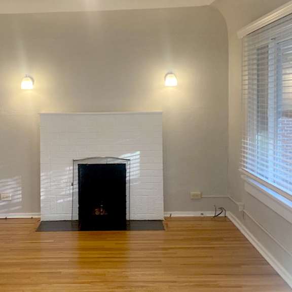 a white fireplace in a room with wooden floors and white walls.
