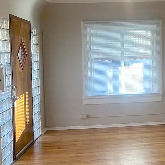 a room with wooden floors and a window with blinds.