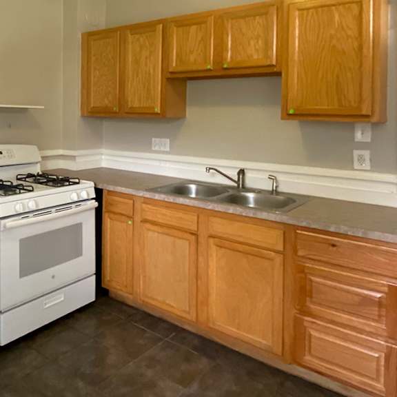 a kitchen with a white refrigerator, stove, and sink.