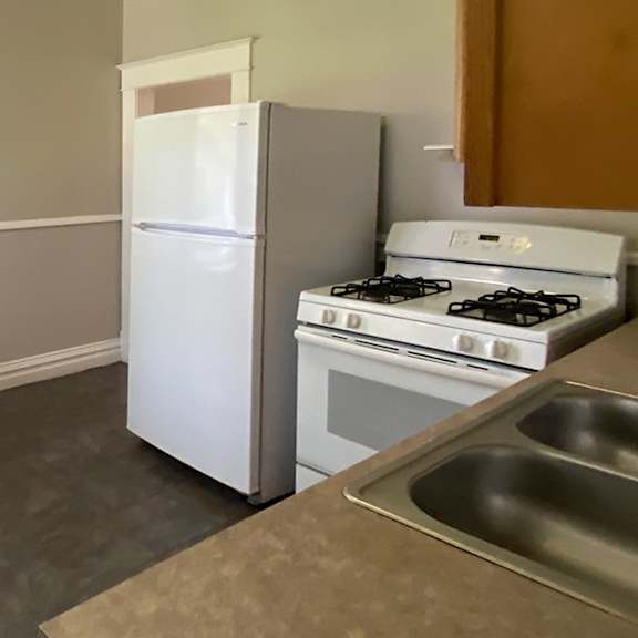 a kitchen with a white refrigerator, stove, and sink.
