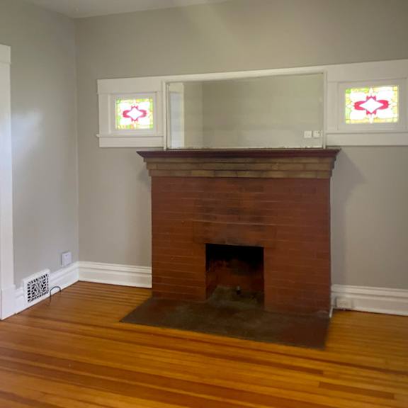 a fireplace with a white mantle and a window to the left.