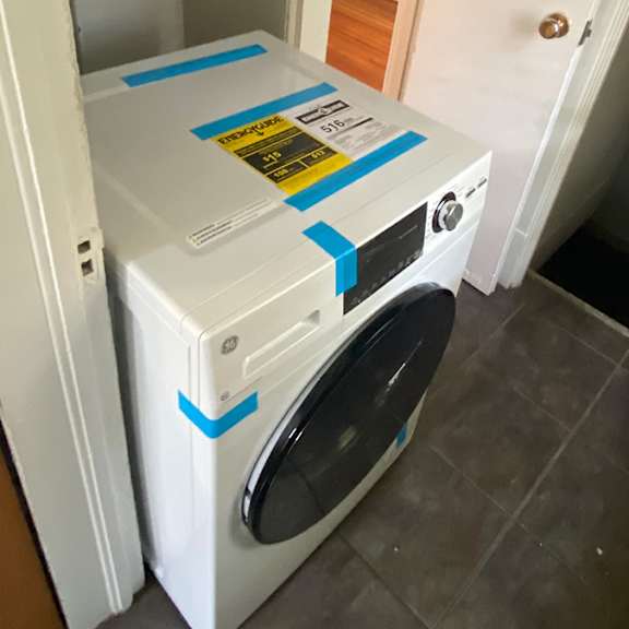 a white washing machine with a blue tape on it.