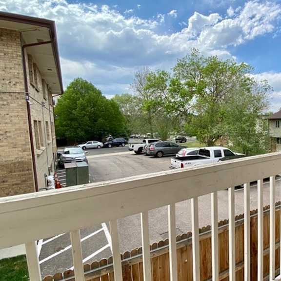 a view from a balcony overlooking a street with cars and houses.