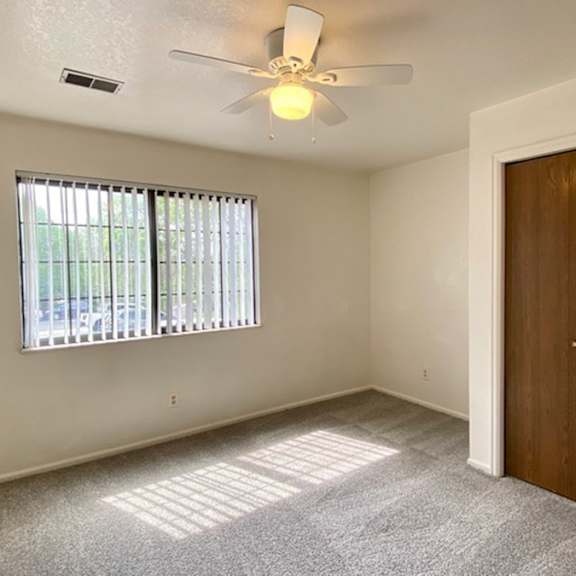 a room with a ceiling fan and a window with blinds.