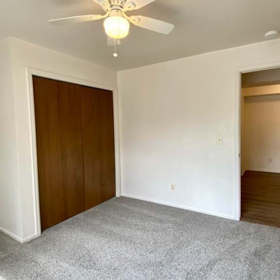 a room with a ceiling fan and carpeted floor.