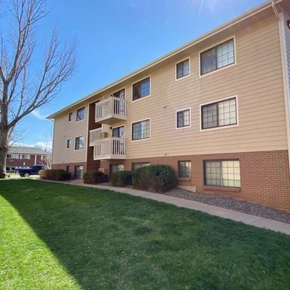 a large apartment building with a green lawn in front.