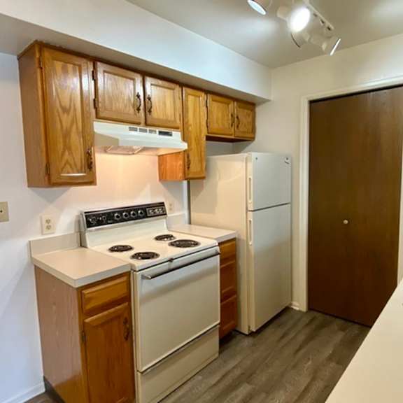 a small kitchen with a white stove and wooden cabinets.