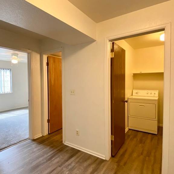 a white room with a wooden floor and a washing machine in the corner.